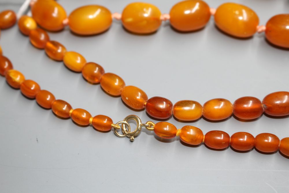 Two single strand graduated oval amber bead necklaces, with yellow metal clasps, one stamped 375,